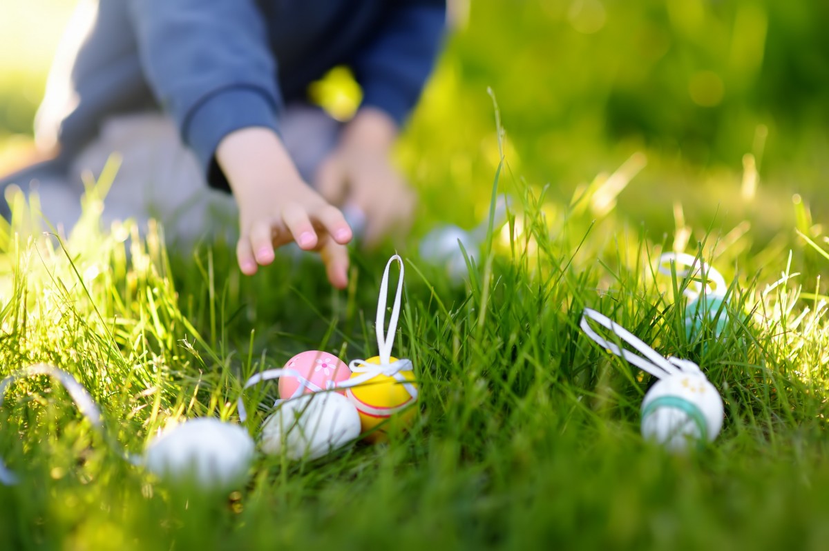 child reaching for Easter egg in grass